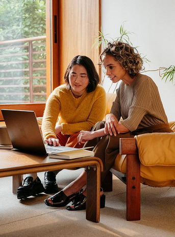 Two colleagues reviewing research on a laptop